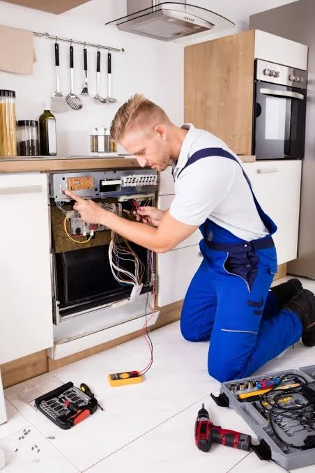 Technician using a meter to inspect an open dishwasher control panel