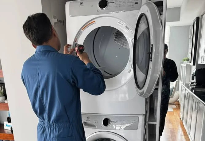Technician servicing the open door area of a stacked dryer