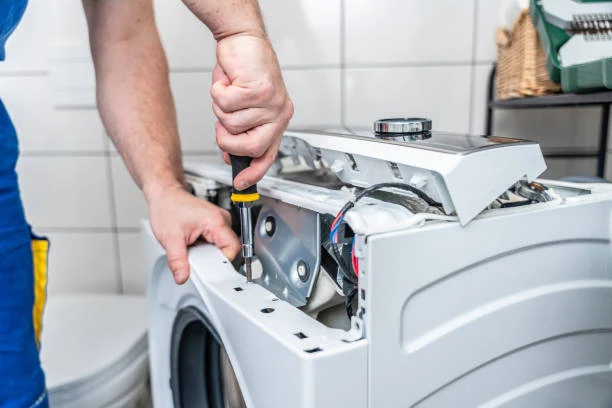 Close-up of a technician working on a washing machine with its top panel removed