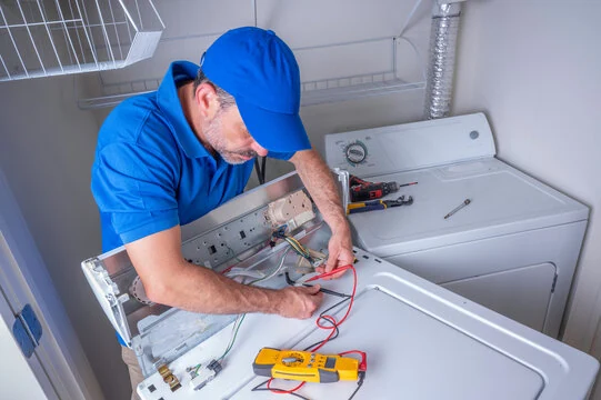 Technician using a multimeter to diagnose a laundry appliance