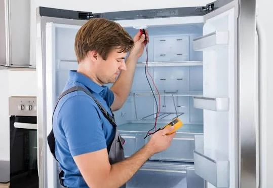 Technician testing the inside of a refrigerator with a multimeter
